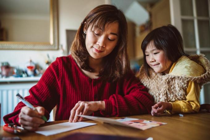 noor kena ema, kes kirjutab kodus oma armsa tütrega perele õnnitluskaarti