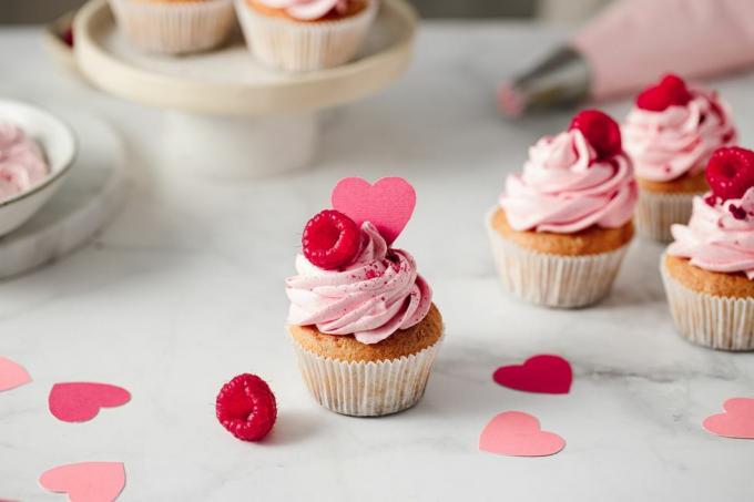 Värskelt valmistatud vaarika koogikesed köögilaual maitsvad roosad koogikesed vaarika ja paberist südamekattega