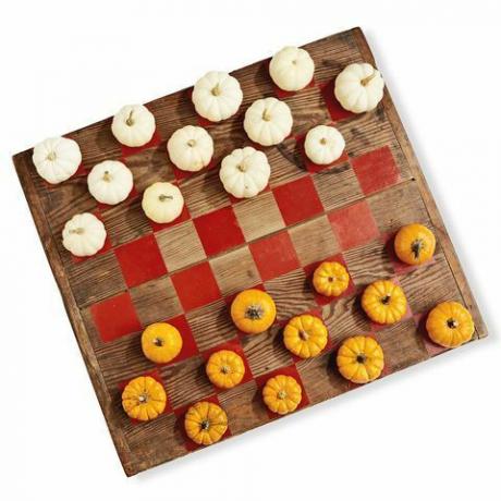 puitlaud, mis on maalitud nagu kabe mäng, kasutades mängudetailidena valge ja oranži mini kõrvitsaid