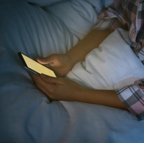 naine, kes kasutab öösel voodis nutitelefoni, lähivõtete nomofoobia ja unehäirete probleem