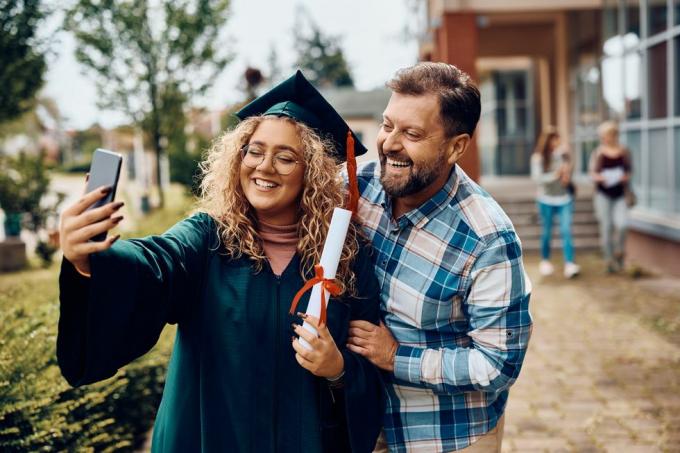 õnnelik ülikoolilõpetaja ja tema isa lõbutseb nutitelefoniga selfie'd tehes